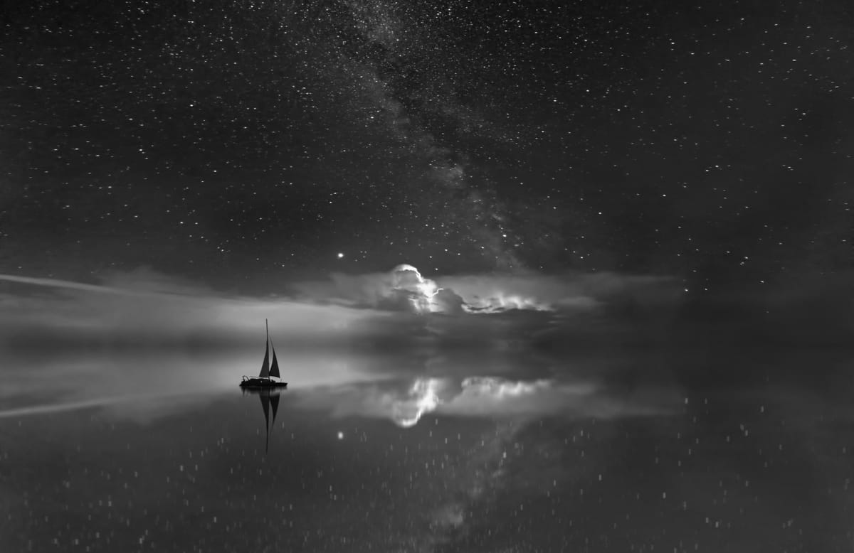 A small sailboat floats on a mirror-like sea under a star-filled sky, with the Milky Way visible. The scene is serene and awe-inspiring.