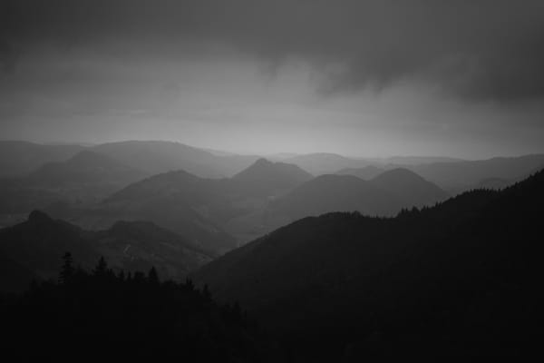 A grayscale panorama of hilly landscapes under an overcast sky. Rolling hills fade into the distance, creating a serene and moody atmosphere.